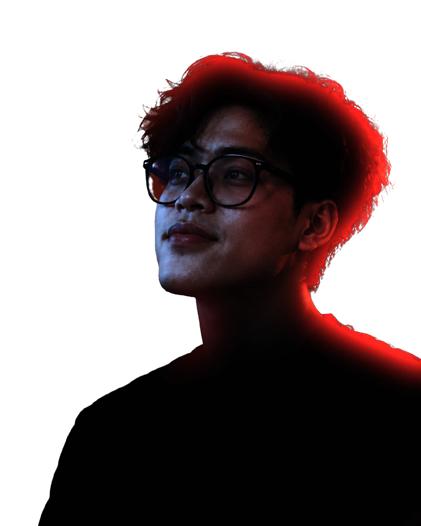 Side portrait of Abu Hafiz in glasses and a black t-shirt, looking up, lit in blue and orange